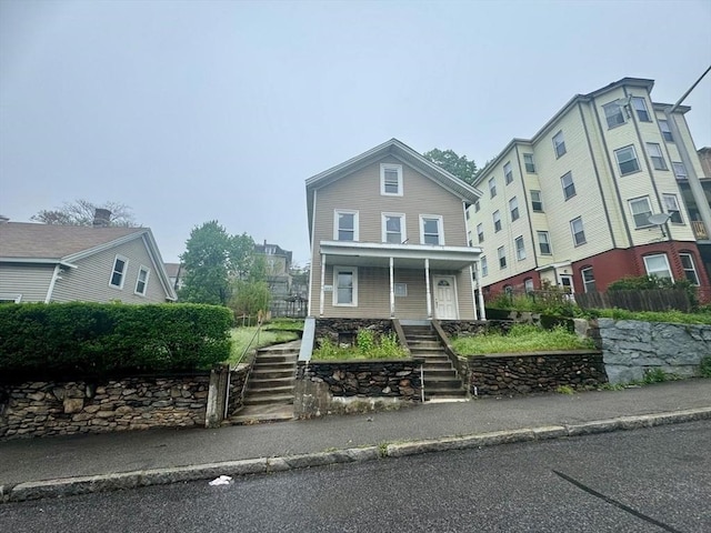 traditional-style house featuring stairway and covered porch