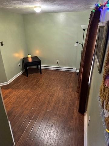 interior space featuring a textured ceiling, dark wood-type flooring, and a baseboard radiator