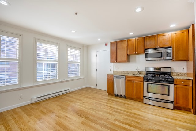 kitchen featuring a baseboard radiator, sink, appliances with stainless steel finishes, and light hardwood / wood-style flooring