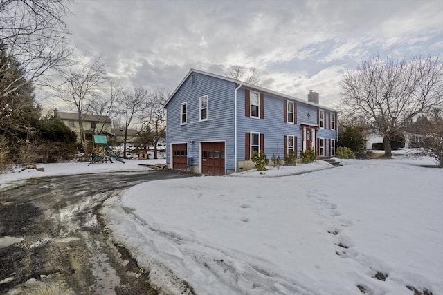 exterior space with aphalt driveway, a chimney, and an attached garage