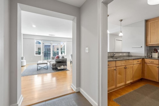 kitchen with open floor plan, light wood finished floors, a sink, and pendant lighting