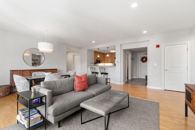 living room featuring light wood-style flooring, baseboards, and recessed lighting