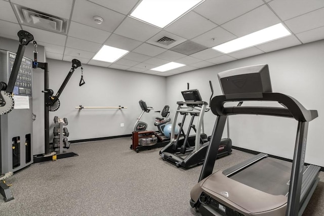 exercise area featuring a paneled ceiling, visible vents, and baseboards