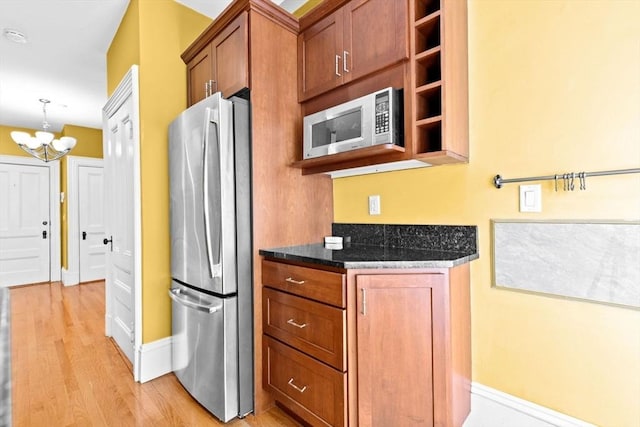 41 Cushing Ave Unit 1, Boston, MA 02125 - kitchen with appliances with stainless steel finishes, a chandelier, light wood-type flooring, brown cabinets, and dark stone counters