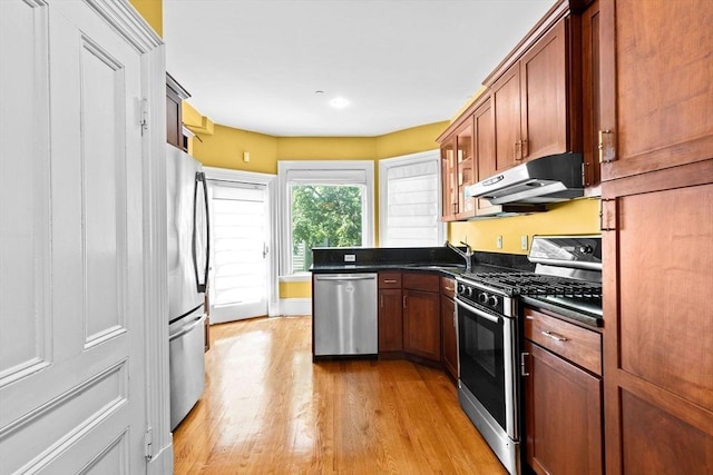 41 Cushing Ave Unit 1, Boston, MA 02125 - kitchen featuring stainless steel appliances, dark countertops, exhaust hood, light wood-style flooring, and brown cabinets
