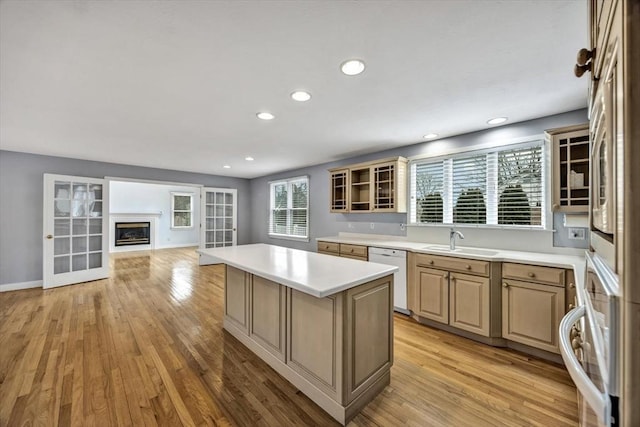 kitchen featuring sink, a kitchen island, light wood-type flooring, white dishwasher, and light brown cabinets