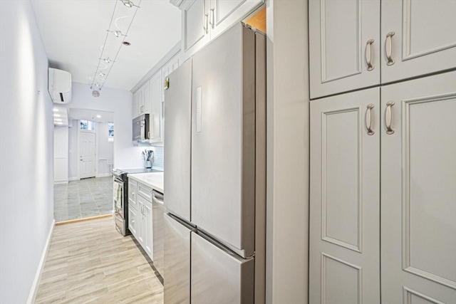 kitchen with white cabinetry, light hardwood / wood-style floors, appliances with stainless steel finishes, backsplash, and a wall mounted air conditioner