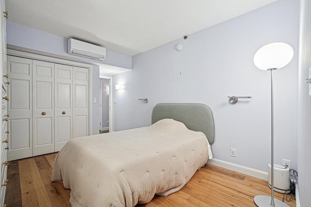 bedroom featuring hardwood / wood-style flooring, a closet, and a wall mounted AC