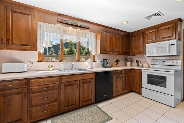 kitchen featuring visible vents, a sink, white appliances, and light countertops