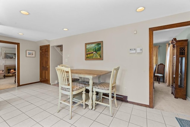 dining room featuring baseboards, recessed lighting, light tile patterned flooring, and a warm lit fireplace