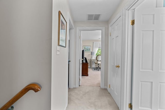 corridor featuring baseboards, visible vents, an upstairs landing, and light colored carpet