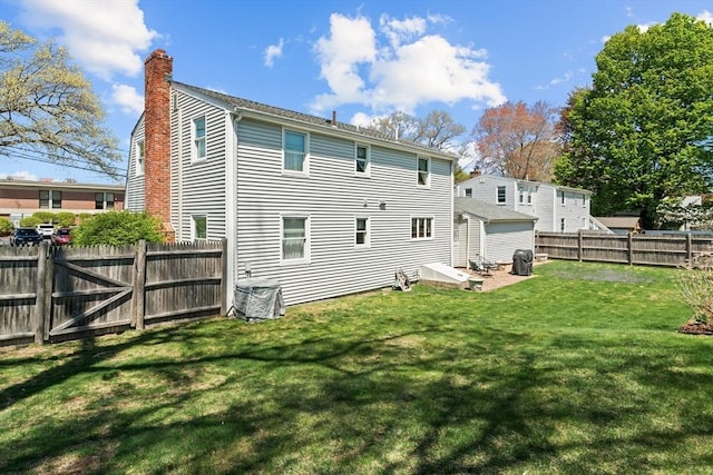 back of property with a yard, a chimney, and a fenced backyard