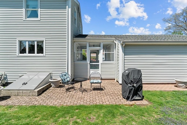 rear view of house featuring a shingled roof, a sunroom, and a patio area