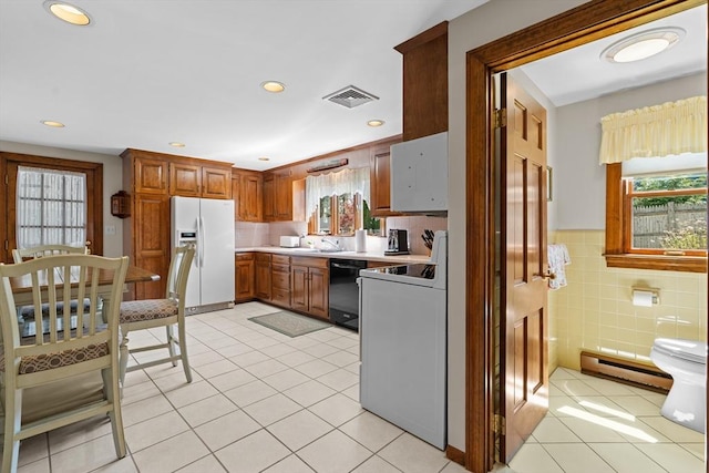 kitchen with light tile patterned flooring, white fridge with ice dispenser, black dishwasher, a baseboard heating unit, and visible vents