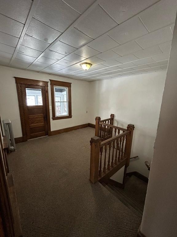 carpeted foyer entrance featuring baseboards