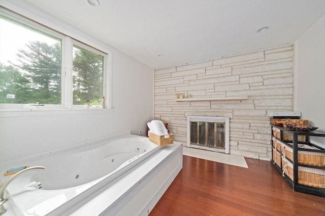 bathroom featuring a tub to relax in, wood-type flooring, and a fireplace