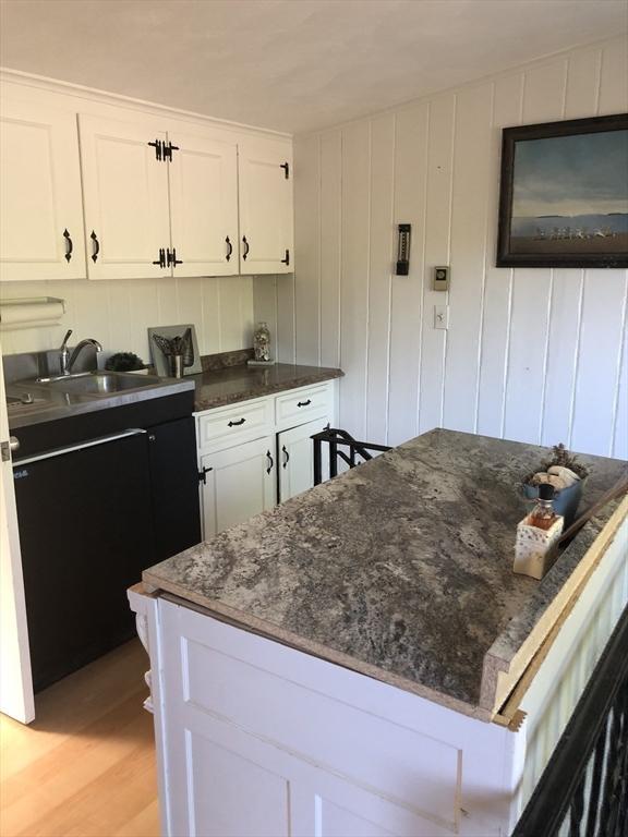 kitchen with white cabinets, a center island, sink, and light hardwood / wood-style flooring