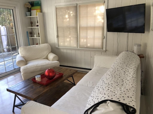 living room with wooden walls, wood-type flooring, and a baseboard heating unit