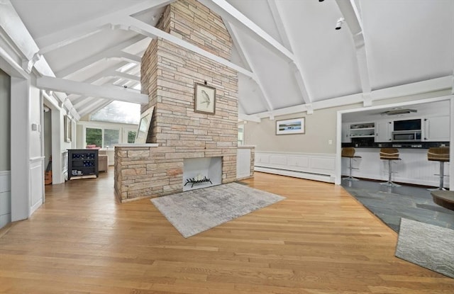 living room with lofted ceiling with beams, a fireplace, a baseboard radiator, and light wood-type flooring