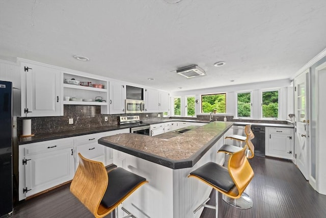 kitchen with a kitchen bar, stainless steel appliances, and white cabinetry