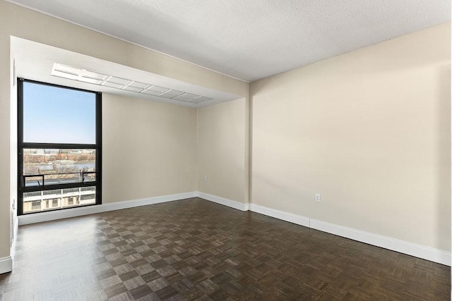 empty room with a textured ceiling and dark parquet floors