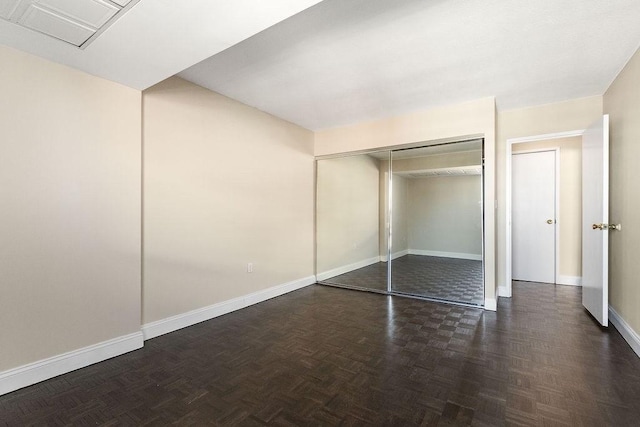 unfurnished bedroom featuring dark parquet floors and a closet