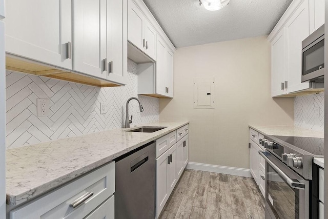 kitchen with light stone counters, sink, white cabinets, and appliances with stainless steel finishes