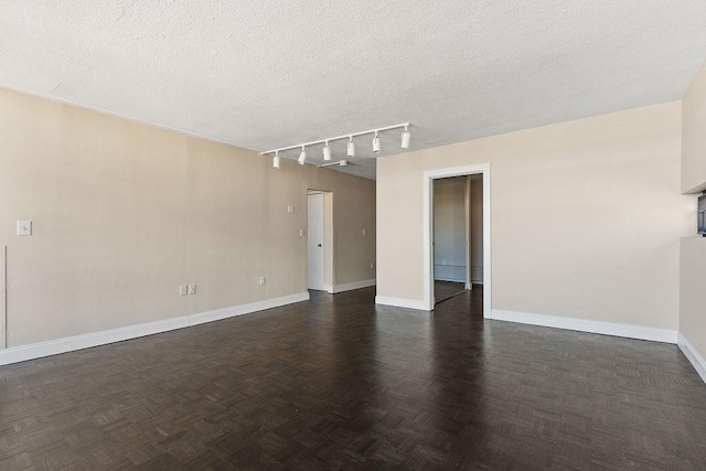 spare room featuring track lighting, dark parquet floors, and a textured ceiling