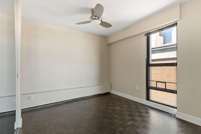 empty room with ceiling fan and dark parquet floors