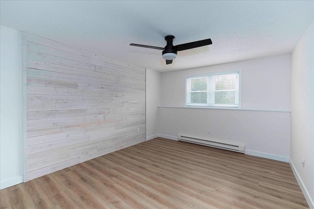 unfurnished room with a baseboard heating unit, wood walls, and wood finished floors