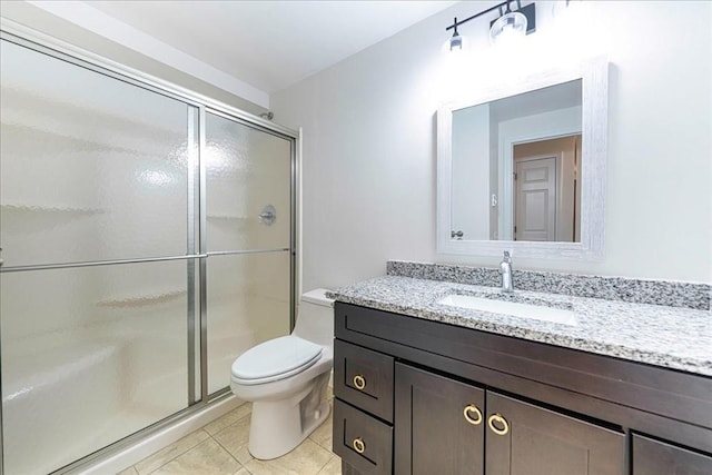 bathroom featuring toilet, a shower stall, vanity, and tile patterned floors