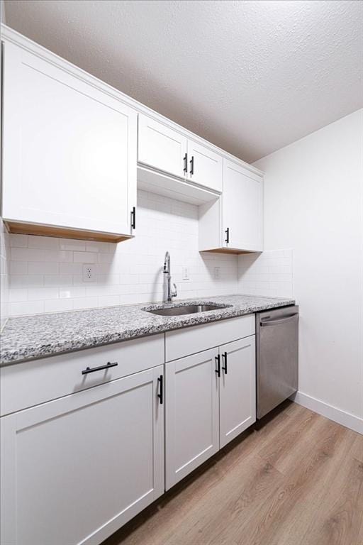 kitchen with dishwasher, a sink, white cabinetry, and light wood-style floors