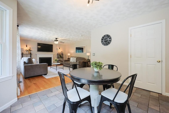 32 Lowe Meadow Ln, North Attleboro, MA 02760 - tiled dining area with ceiling fan, a textured ceiling, a fireplace, and baseboards