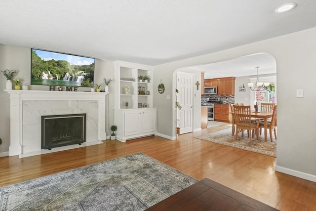 167 Montaup Ave, Dracut, MA 01826 - living area featuring wood finished floors, arched walkways, baseboards, a fireplace, and a chandelier