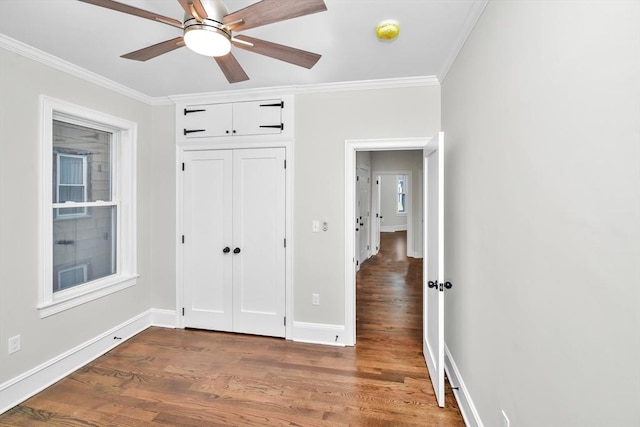 unfurnished bedroom with ceiling fan, crown molding, dark wood-type flooring, and a closet