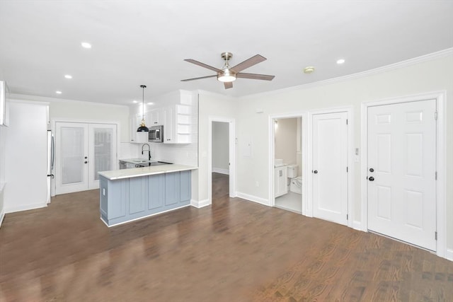 kitchen featuring kitchen peninsula, appliances with stainless steel finishes, dark wood-type flooring, decorative light fixtures, and white cabinets