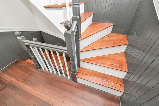 stairway with wooden walls and hardwood / wood-style floors