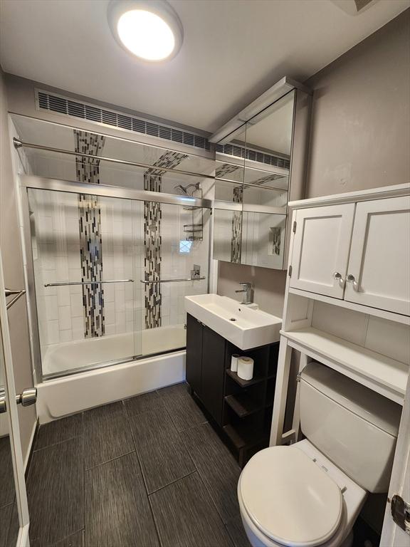 full bathroom featuring shower / bath combination with glass door, toilet, and vanity