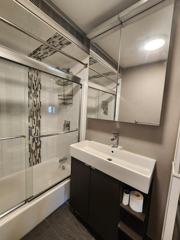 bathroom featuring wood finished floors and enclosed tub / shower combo