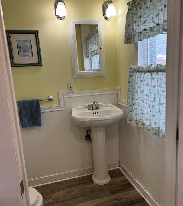 half bathroom with toilet and wood finished floors