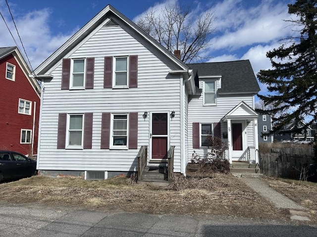 traditional home featuring a shingled roof, entry steps, and a chimney