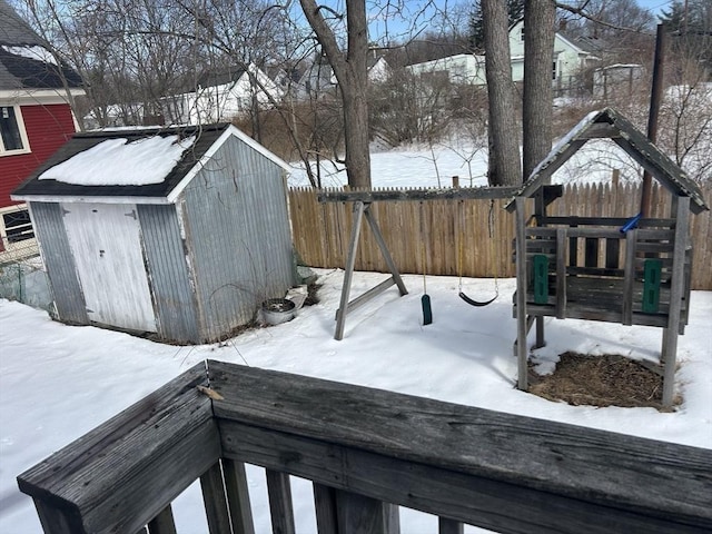 yard covered in snow with a fenced backyard, an outdoor structure, and a storage shed