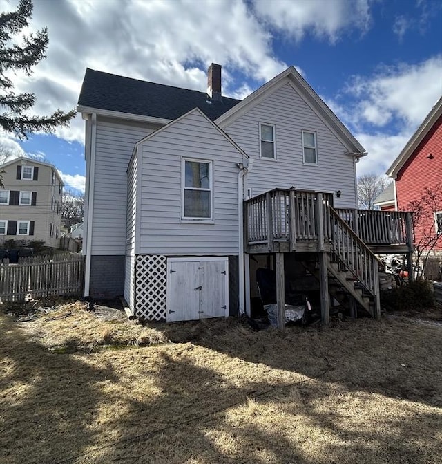 rear view of house with a deck, stairway, a chimney, and fence