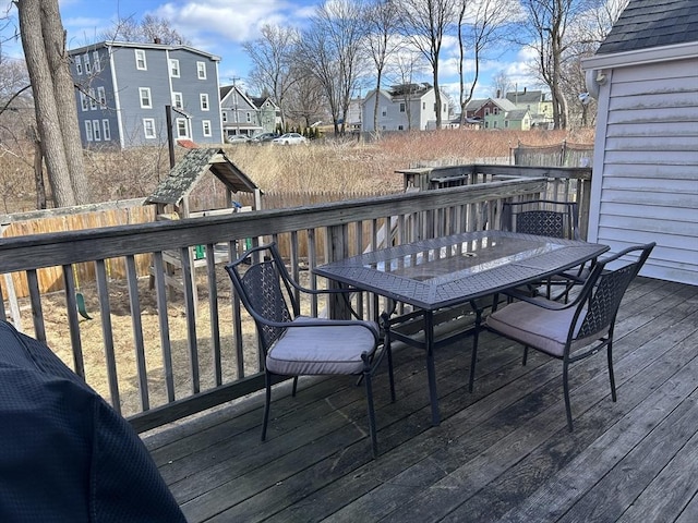 wooden terrace featuring outdoor dining area, a fenced backyard, and a residential view