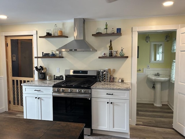 kitchen featuring ornamental molding, gas stove, wall chimney range hood, and open shelves