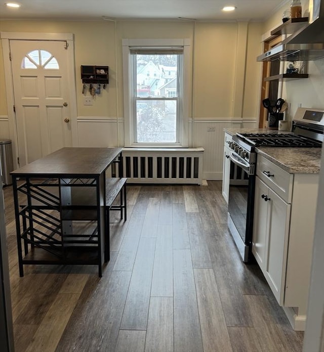 kitchen featuring stainless steel range with gas cooktop, dark wood-style flooring, and wainscoting