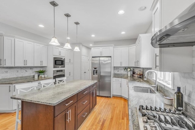 52 Sylvan Dr, Stow, MA 01775 - kitchen featuring appliances with stainless steel finishes, wall chimney exhaust hood, a kitchen island, white cabinetry, and tasteful backsplash