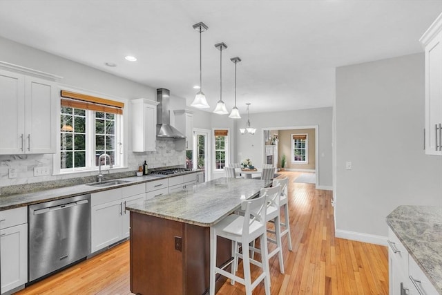 52 Sylvan Dr, Stow, MA 01775 - kitchen featuring appliances with stainless steel finishes, wall chimney range hood, decorative backsplash, a kitchen bar, and white cabinets