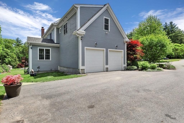 52 Sylvan Dr, Stow, MA 01775 - view of home's exterior featuring an attached garage, a chimney, and asphalt driveway