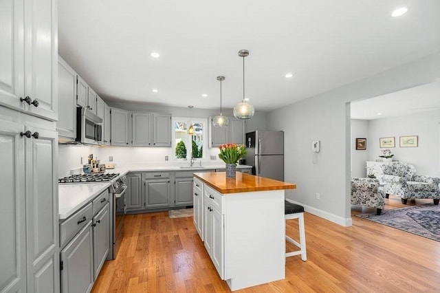 kitchen with recessed lighting, a sink, appliances with stainless steel finishes, and gray cabinetry